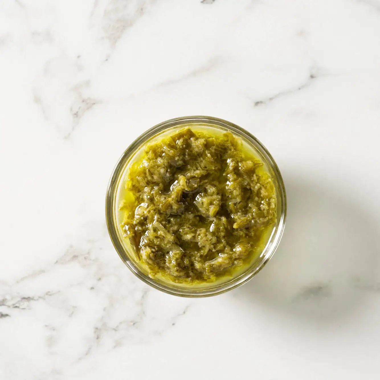 A vibrant green garlic scallion sauce in a clear glass jar ideal for flavorful cooking and dipping