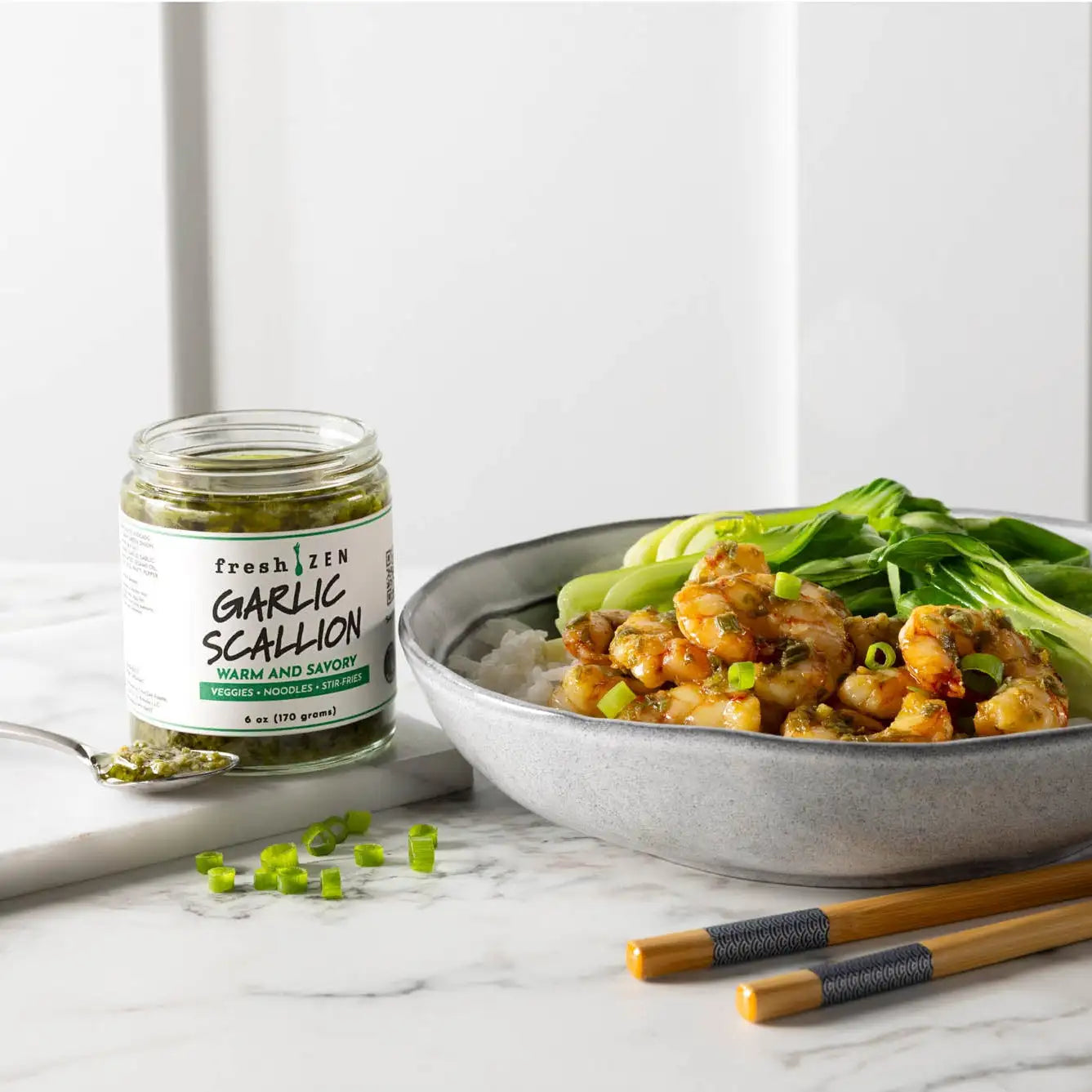 Bowl of shrimp and rice with vegan garlic scallion seasoning jar on a marble surface