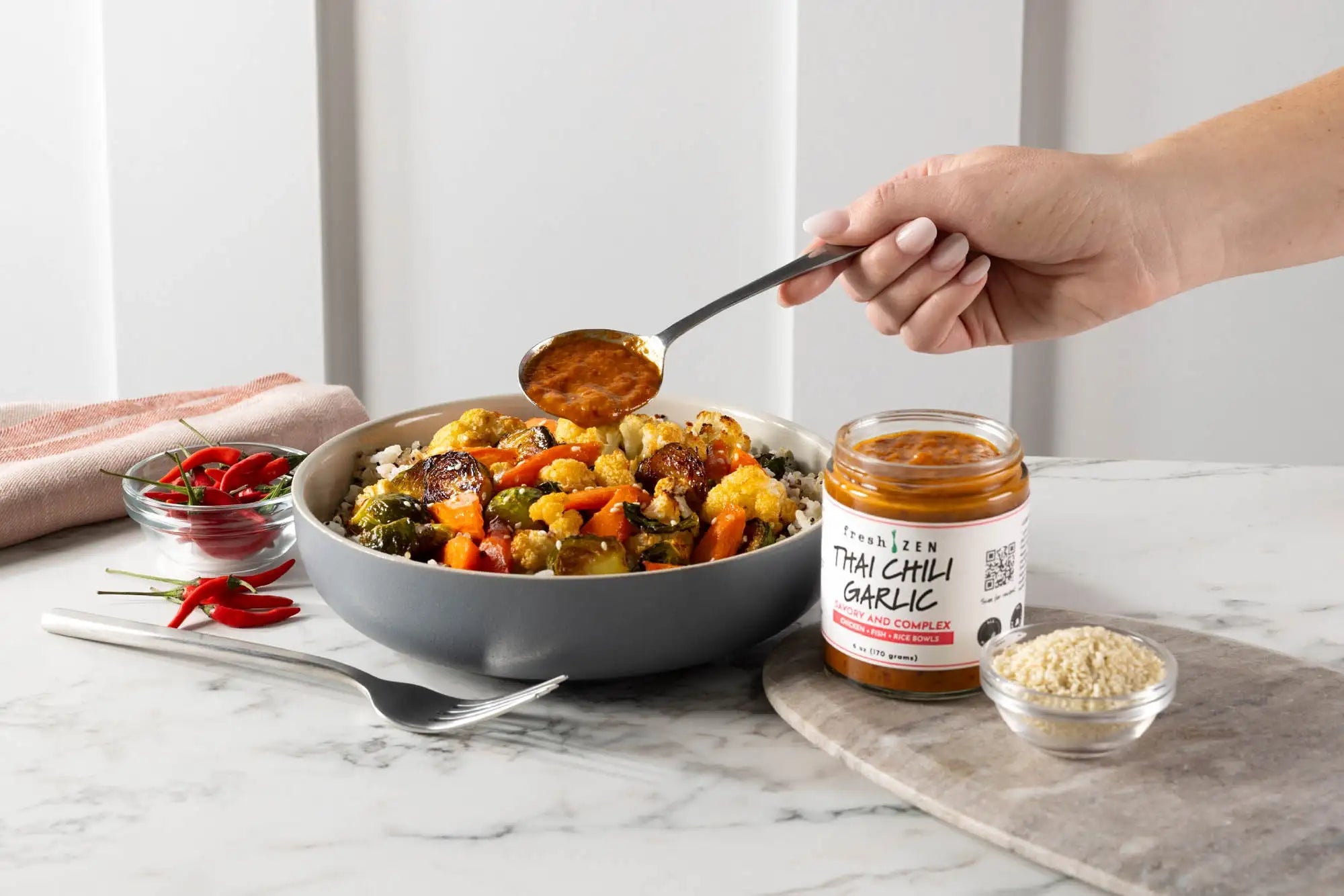 A jar of freshzen thai chili garlic sauce with a white label and red text, containing an orange-red paste inside.