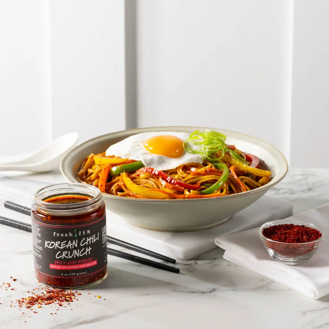 A jar of fresh zen korean chili crunch sauce vibrant red spicy chili paste in a clear glass container with a black label