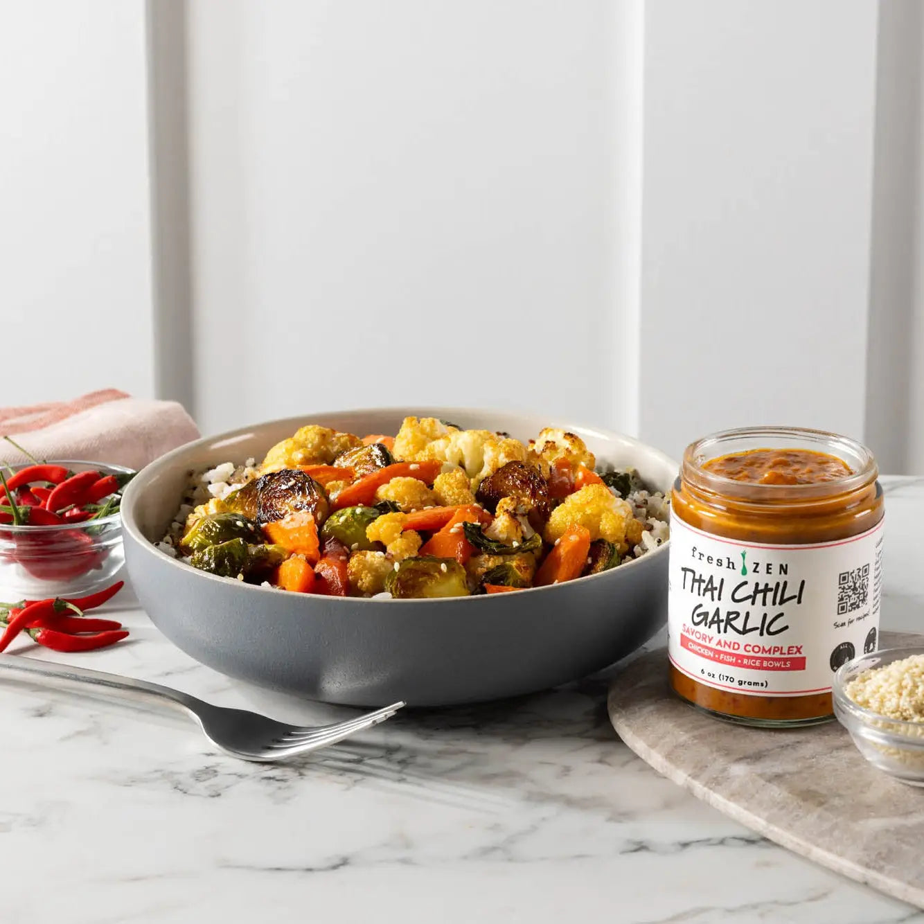 Gray ceramic bowl filled with roasted vegetables and rice showcasing thai chili garlic sauce use in a meal