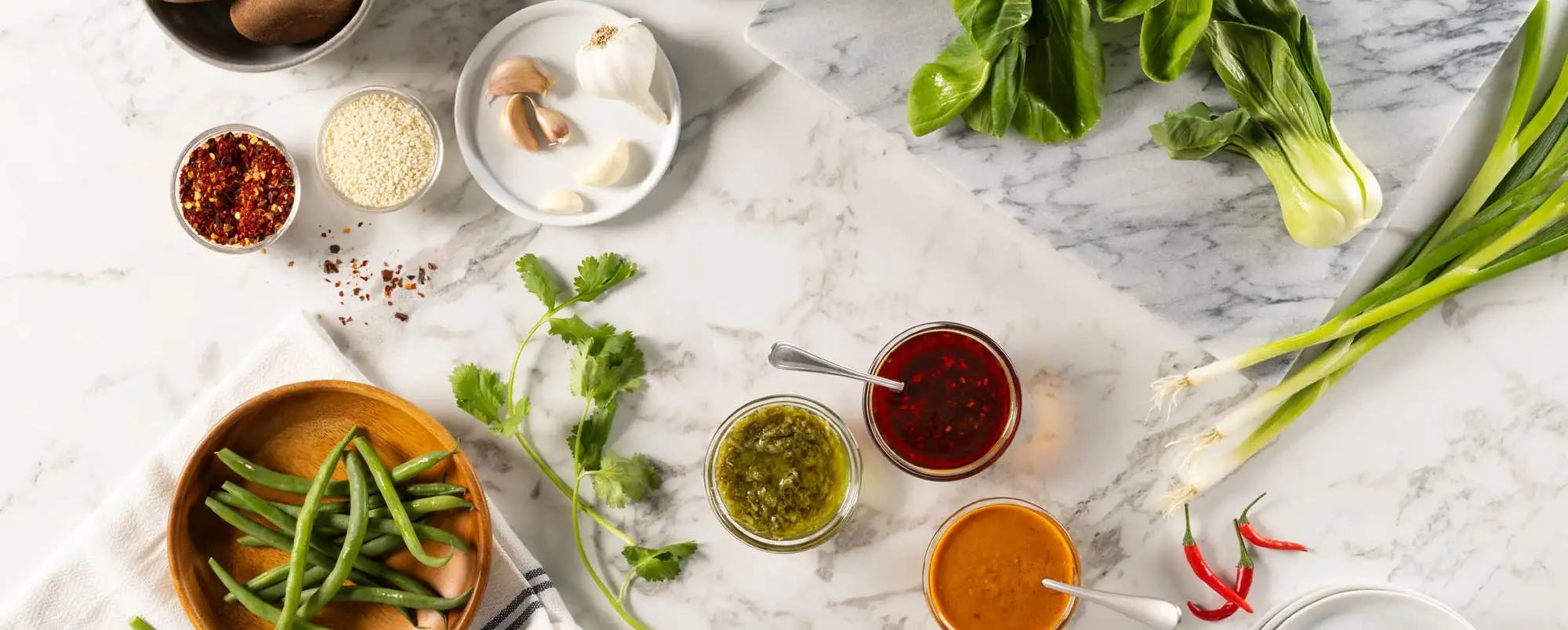 Assorted clean ingredients and asian-inspired condiments on a marble surface